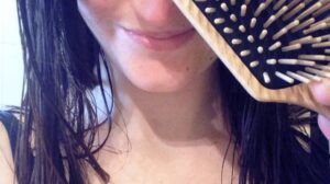 mujer cepillando su cabello con cepillo de madera para un pelo más sano