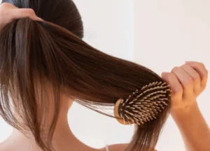 mujer cepillando el cabello correctamente con cepillo de madera